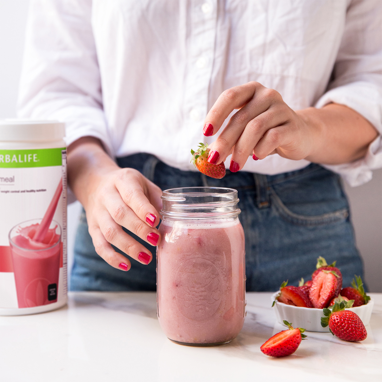Mujer haciendo batido de fresa de Herbalife Nutricition